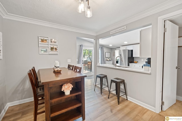 6458 Decatur St, Omaha, NE 68104 - dining space featuring crown molding, light wood finished floors, baseboards, and a textured ceiling
