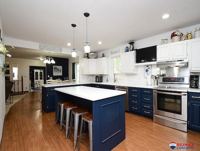 105 Nebraska St, Murdock, NE 68407 - kitchen with stainless steel appliances, blue cabinetry, under cabinet range hood, light countertops, and a kitchen island