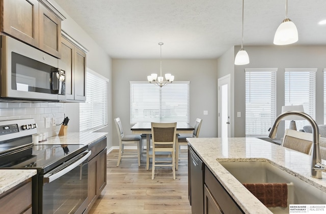 11745 S 113th St, Papillion, NE 68046 - kitchen with appliances with stainless steel finishes, a sink, light wood-style flooring, backsplash, and a chandelier
