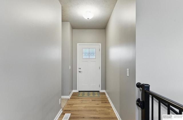 11745 S 113th St, Papillion, NE 68046 - doorway to outside featuring light wood-type flooring, baseboards, and a textured ceiling