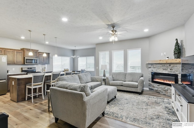 11745 S 113th St, Papillion, NE 68046 - living area with a ceiling fan, a textured ceiling, recessed lighting, light wood-style flooring, and a stone fireplace
