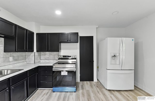 2544 N 64th St, Omaha, NE 68104 - kitchen with white refrigerator with ice dispenser, stainless steel electric range oven, dark cabinetry, and light wood finished floors