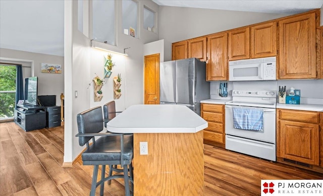 6718 Aspen St, La Vista, NE 68128 - kitchen with white appliances, light countertops, light wood-style floors, high vaulted ceiling, and brown cabinets