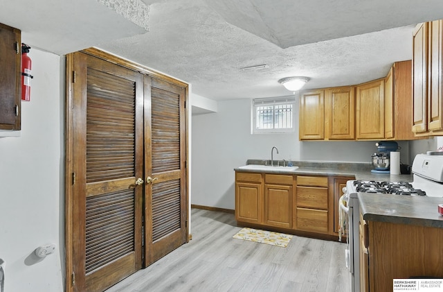 6920 N 30th St, Omaha, NE 68112 - kitchen featuring white gas stove, a sink, light wood-style flooring, baseboards, and dark countertops