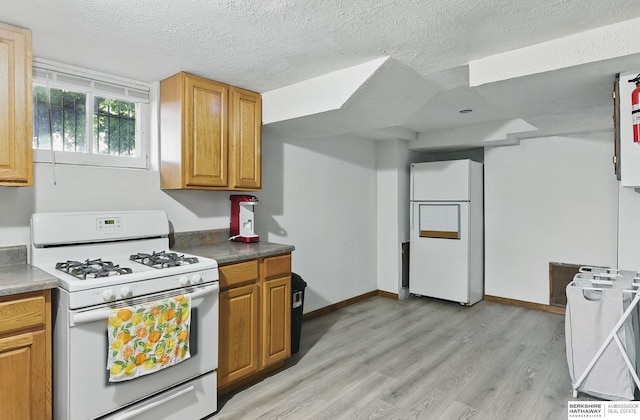 6920 N 30th St, Omaha, NE 68112 - kitchen with white appliances, light wood-style flooring, baseboards, a textured ceiling, and brown cabinets