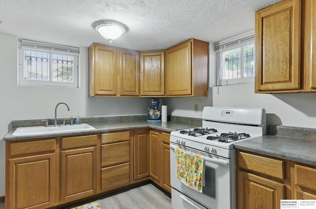 6920 N 30th St, Omaha, NE 68112 - kitchen featuring white gas range oven, a sink, a textured ceiling, brown cabinetry, and light wood-type flooring