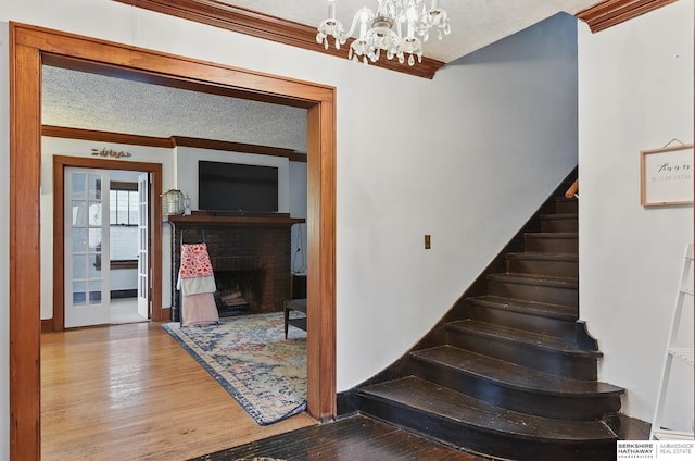 6920 N 30th St, Omaha, NE 68112 - stairway featuring ornamental molding, a chandelier, wood finished floors, a textured ceiling, and a fireplace