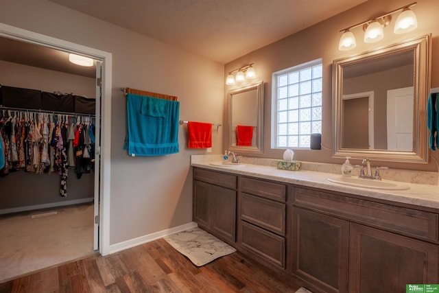 6311 N 169th St, Omaha, NE 68116 - bathroom with double vanity, wood finished floors, baseboards, and a walk in closet