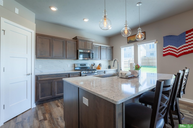 6311 N 169th St, Omaha, NE 68116 - kitchen with stainless steel appliances, a sink, an island with sink, light stone counters, and a breakfast bar