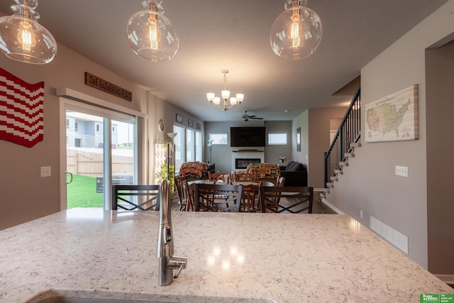 6311 N 169th St, Omaha, NE 68116 - kitchen with a chandelier, a fireplace, a sink, pendant lighting, and light stone countertops