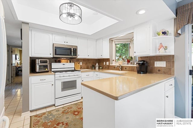 15341 Davenport Cir, Omaha, NE 68154 - kitchen with white gas stove, stainless steel microwave, a sink, light tile patterned floors, and a peninsula