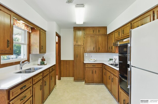 4314 Oak St, Omaha, NE 68105 - kitchen with freestanding refrigerator, a sink, a warming drawer, brown cabinetry, and wainscoting