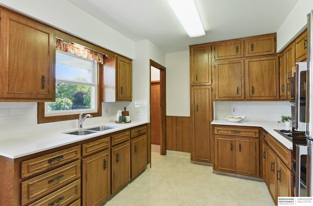 4314 Oak St, Omaha, NE 68105 - kitchen featuring a sink, brown cabinetry, light countertops, and a wainscoted wall