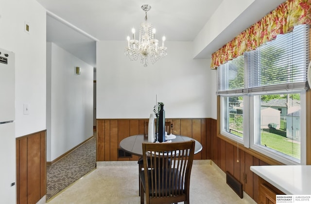 4314 Oak St, Omaha, NE 68105 - dining space featuring wainscoting, a chandelier, wooden walls, and light colored carpet