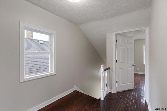 3013 Decatur St, Omaha, NE 68111 - hallway featuring an upstairs landing, a textured ceiling, dark wood-style floors, vaulted ceiling, and baseboards
