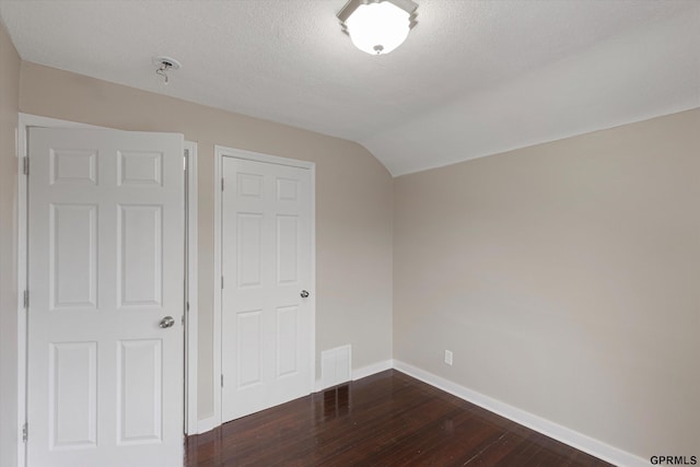 3013 Decatur St, Omaha, NE 68111 - unfurnished bedroom featuring dark wood-style floors, baseboards, a textured ceiling, and lofted ceiling