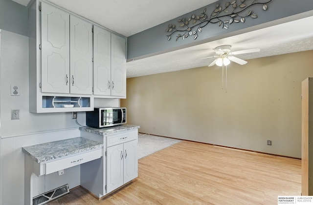 128 S 110th St, Omaha, NE 68154 - kitchen with stainless steel microwave, ceiling fan, light wood finished floors, and light countertops