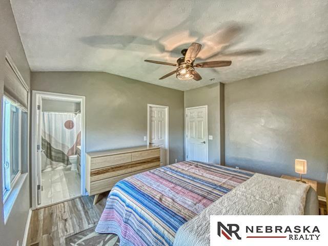 14603 Nebraska Cir, Omaha, NE 68116 - bedroom with wood finished floors, lofted ceiling, a ceiling fan, and ensuite bath