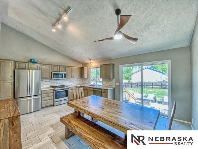 14603 Nebraska Cir, Omaha, NE 68116 - kitchen with appliances with stainless steel finishes, backsplash, light countertops, light tile patterned floors, and a ceiling fan