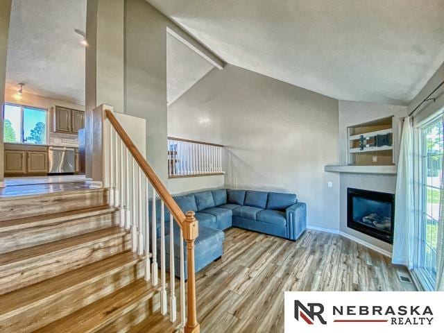 14603 Nebraska Cir, Omaha, NE 68116 - unfurnished living room featuring wood finished floors, a glass covered fireplace, and stairway