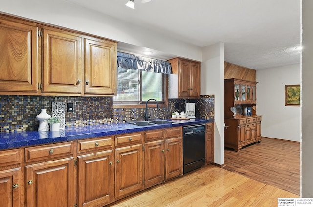301 Oakridge Ct, Bellevue, NE 68005 - kitchen with black dishwasher, a sink, brown cabinetry, dark countertops, and backsplash