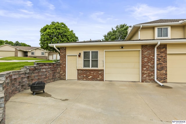 13952 Frederick Cir, Omaha, NE 68138 - view of front of property featuring brick siding, a garage, a fire pit, and driveway