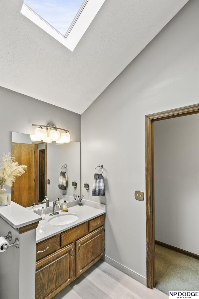 13952 Frederick Cir, Omaha, NE 68138 - bathroom featuring vanity, a skylight, wood finished floors, and baseboards