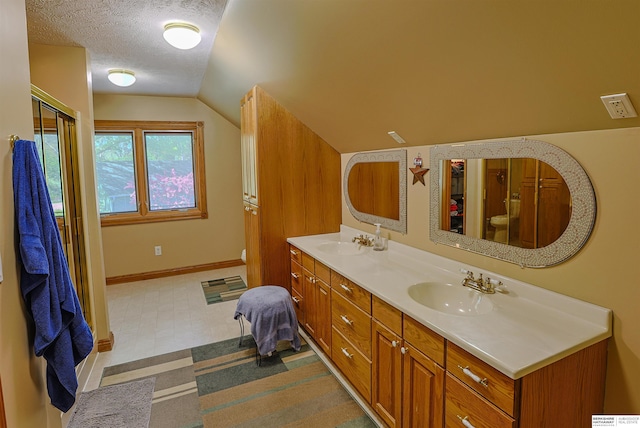 5531 County Road 34, Fort Calhoun, NE 68023 - full bath featuring lofted ceiling, double vanity, toilet, a textured ceiling, and baseboards
