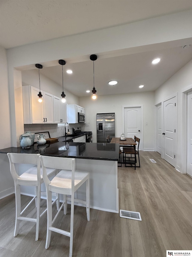 914 S 26th St, Omaha, NE 68105 - kitchen with stainless steel appliances, a sink, dark countertops, a peninsula, and light wood-style flooring