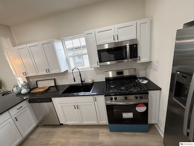 914 S 26th St, Omaha, NE 68105 - kitchen featuring stainless steel appliances, a sink, white cabinets, and light wood-style floors
