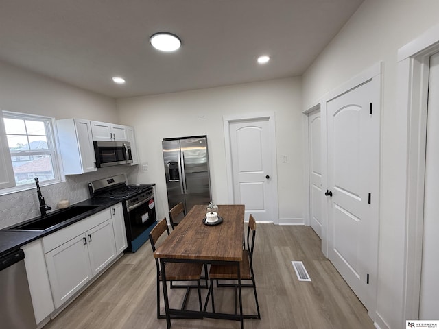 914 S 26th St, Omaha, NE 68105 - kitchen with appliances with stainless steel finishes, a sink, dark countertops, light wood-type flooring, and recessed lighting