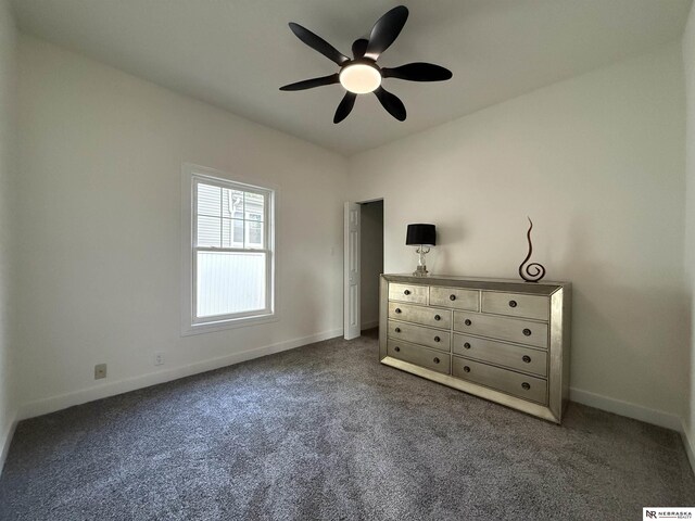 914 S 26th St, Omaha, NE 68105 - unfurnished bedroom with dark carpet, baseboards, and a ceiling fan