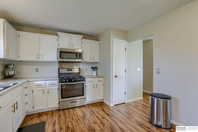 14014 S 35th St, Bellevue, NE 68123 - kitchen with appliances with stainless steel finishes, light wood finished floors, and white cabinetry
