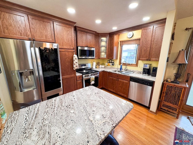 1507 SW 13th St, Lincoln, NE 68522 - kitchen with appliances with stainless steel finishes, a sink, light wood-style floors, light stone countertops, and brown cabinets