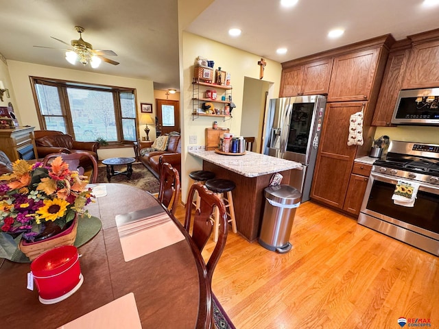 1507 SW 13th St, Lincoln, NE 68522 - kitchen featuring appliances with stainless steel finishes, light wood-style flooring, ceiling fan, a breakfast bar, and open floor plan