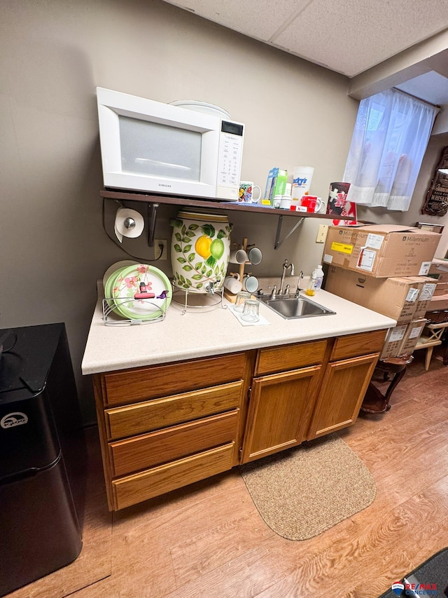 1507 SW 13th St, Lincoln, NE 68522 - kitchen with a sink, white microwave, brown cabinetry, and light wood-style floors