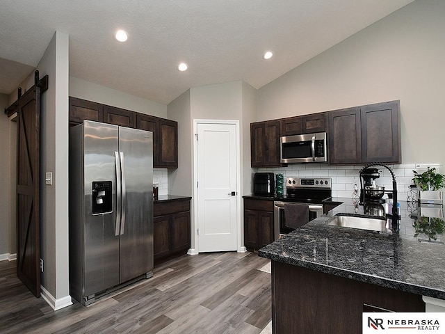 4062 W Gary Gately St, Lincoln, NE 68528 - kitchen with appliances with stainless steel finishes, a sink, wood finished floors, dark brown cabinetry, and vaulted ceiling