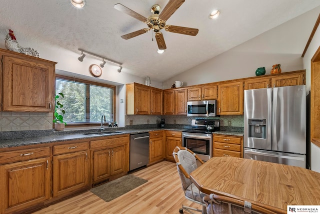 5082 S 149th Ct, Omaha, NE 68137 - kitchen featuring stainless steel appliances, a sink, brown cabinetry, light wood-type flooring, and vaulted ceiling