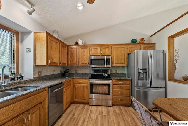 5082 S 149th Ct, Omaha, NE 68137 - kitchen featuring stainless steel appliances, a sink, brown cabinetry, decorative backsplash, and lofted ceiling