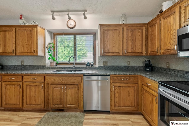 5082 S 149th Ct, Omaha, NE 68137 - kitchen with appliances with stainless steel finishes, a sink, brown cabinets, light wood-style flooring, and dark countertops