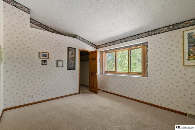 5082 S 149th Ct, Omaha, NE 68137 - carpeted empty room featuring wallpapered walls, a textured ceiling, vaulted ceiling, and baseboards