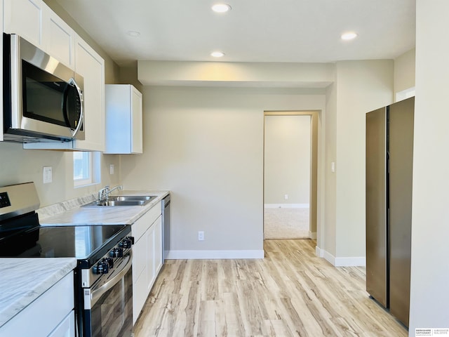 6916 N 24th St, Omaha, NE 68112 - kitchen with appliances with stainless steel finishes, light wood-style floors, white cabinetry, light countertops, and baseboards