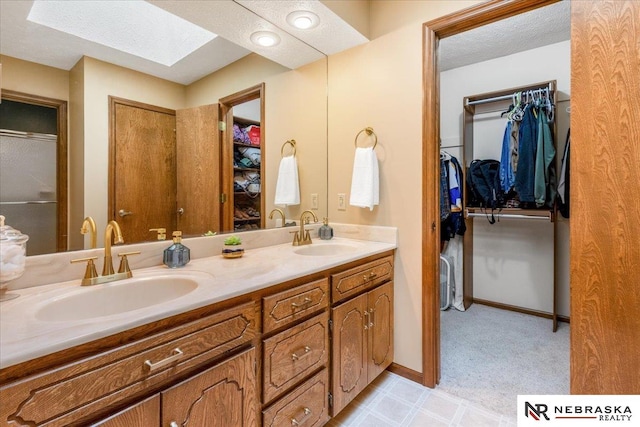 926 Iron Rd, Papillion, NE 68046 - full bathroom with a skylight, double vanity, a walk in closet, a textured ceiling, and baseboards