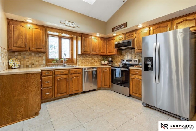 926 Iron Rd, Papillion, NE 68046 - kitchen with stainless steel appliances, a sink, brown cabinets, lofted ceiling, and tasteful backsplash