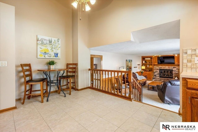 926 Iron Rd, Papillion, NE 68046 - dining room with a high ceiling, a brick fireplace, baseboards, a ceiling fan, and light tile patterned flooring
