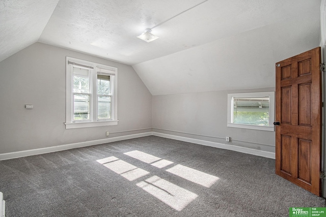 1320 N 40th St, Omaha, NE 68131 - additional living space with vaulted ceiling, dark carpet, baseboards, healthy amount of natural light, and a textured ceiling