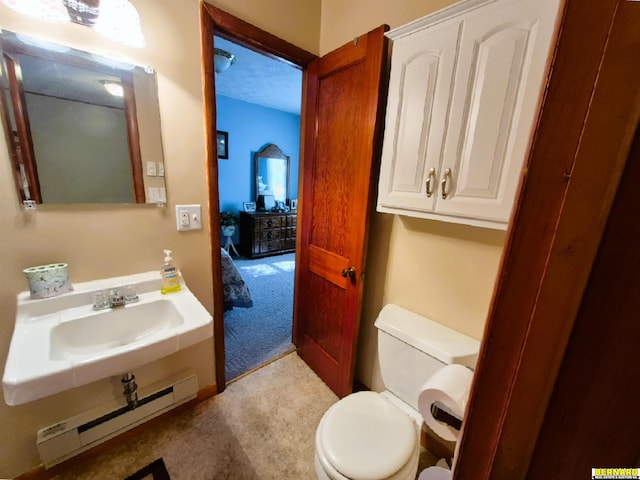 1112 10th St, Auburn, NE 68305 - bathroom featuring a baseboard heating unit, toilet, and a sink