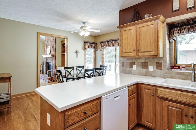 8112 Molokai Dr, Papillion, NE 68046 - kitchen with white dishwasher, a sink, a peninsula, a ceiling fan, and light wood-style floors