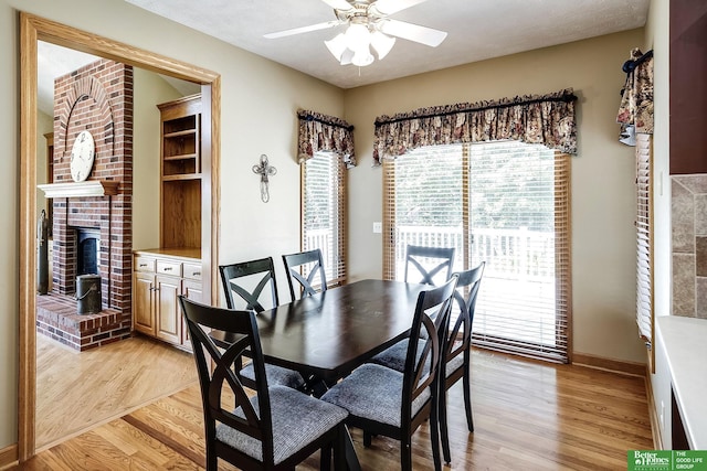 8112 Molokai Dr, Papillion, NE 68046 - dining room with light wood-style flooring, ceiling fan, a brick fireplace, and baseboards