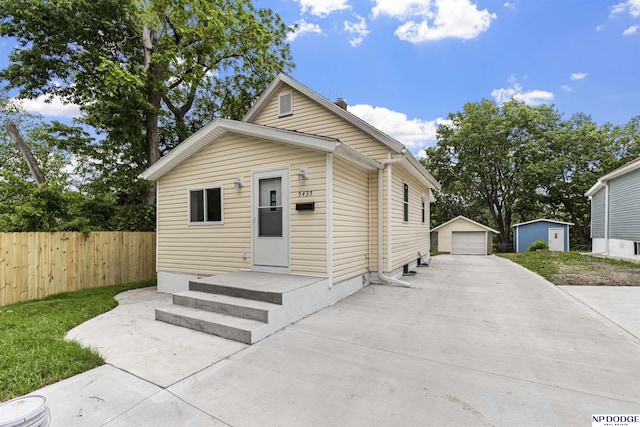 5435 S 18th St, Omaha, NE 68107 - shotgun-style home with concrete driveway, a detached garage, and an outbuilding
